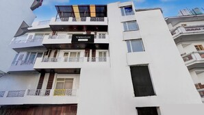 Um edifício de vários andares com varandas, um letreiro com a palavra 'TOWNHOUSE' e céu claro.