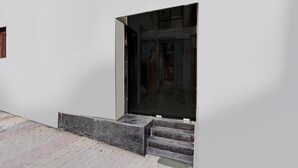 Entrada de um edifício moderno com porta de vidro, degraus e chão de tijolos.