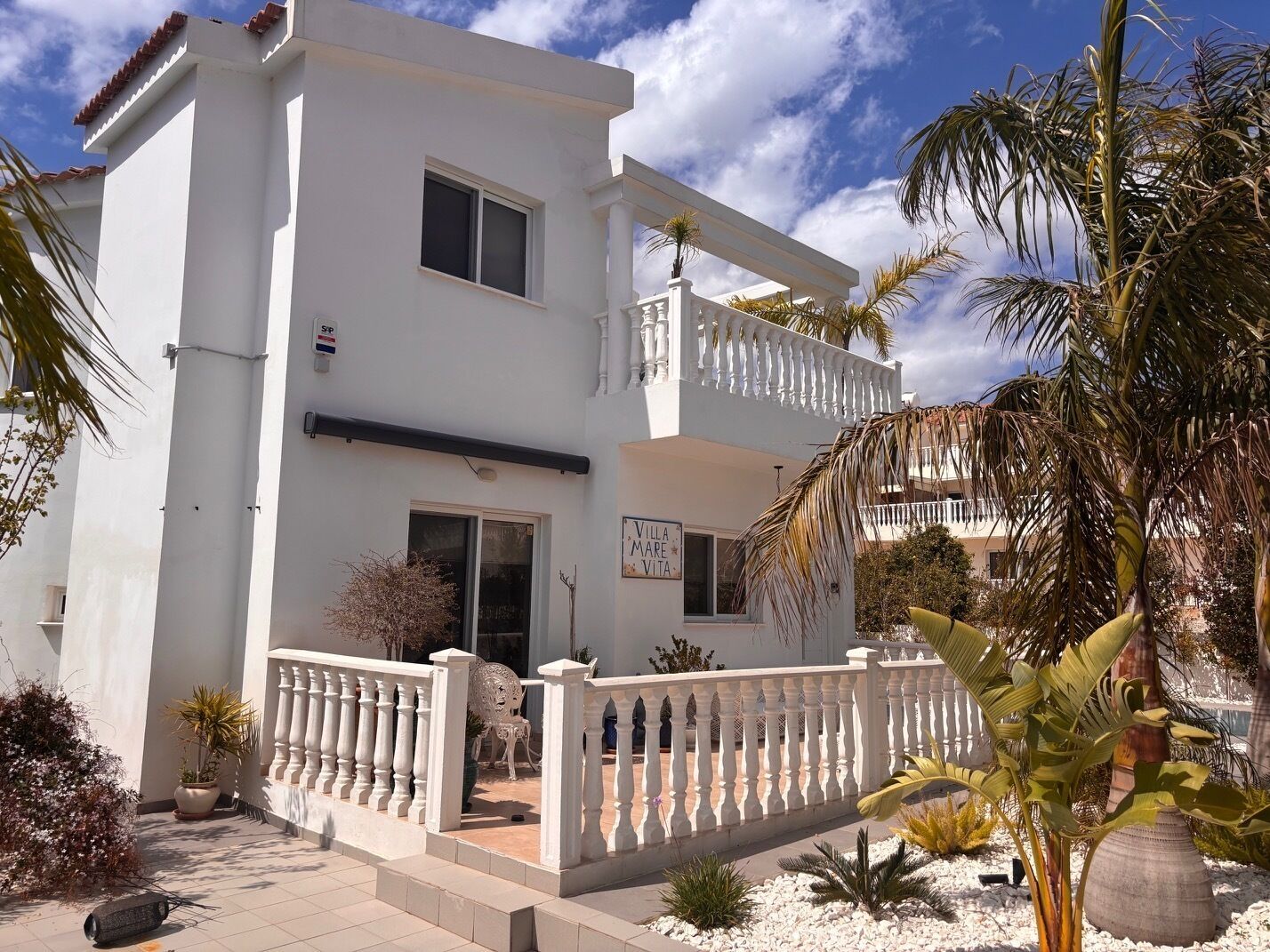 A two-story building with a white exterior, a balcony on the second floor, and a sign that reads 'Villa Mare Vero.'