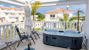 Ein Balkon mit Whirlpool, Stühlen und einem Tisch.