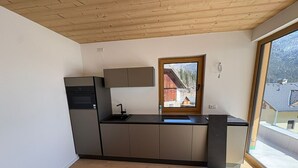 A modern kitchen with a wooden ceiling, a window with a view of a building, and a built-in sink.