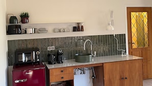A compact kitchen with a microwave, coffee maker, sink, and a red appliance. - Stylish, Sustainable Apartment in Bree (Bree)