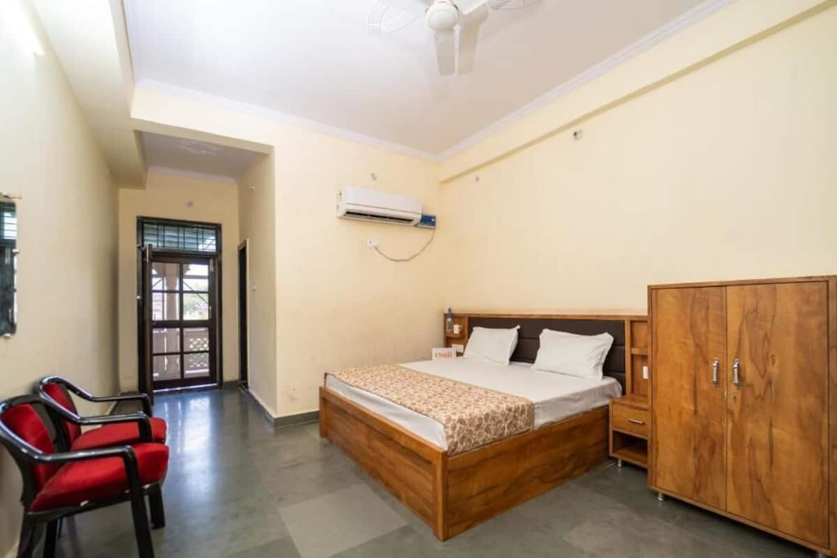 Une chambre à coucher comprenant un lit, une armoire, une chaise, un appareil de climatisation et une porte.