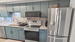 Una cocina moderna con electrodomésticos de acero inoxidable, armarios color turquesa y salpicadero de azulejos.