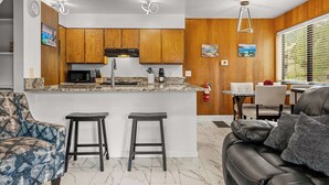 Une cuisine moderne avec des meubles en bois, un plan de travail en marbre et un îlot central doté de tabourets.
