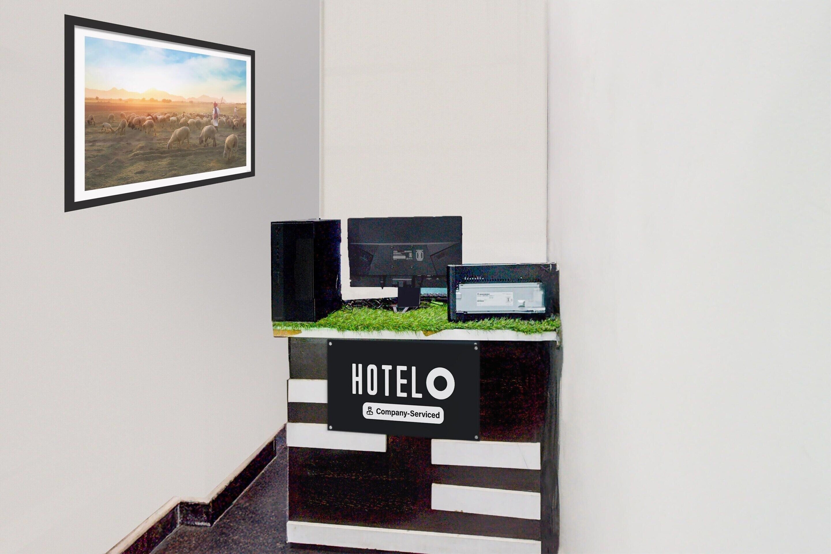 A reception desk with a sign reading 'HOTEL O' and a framed picture of a landscape on the wall.