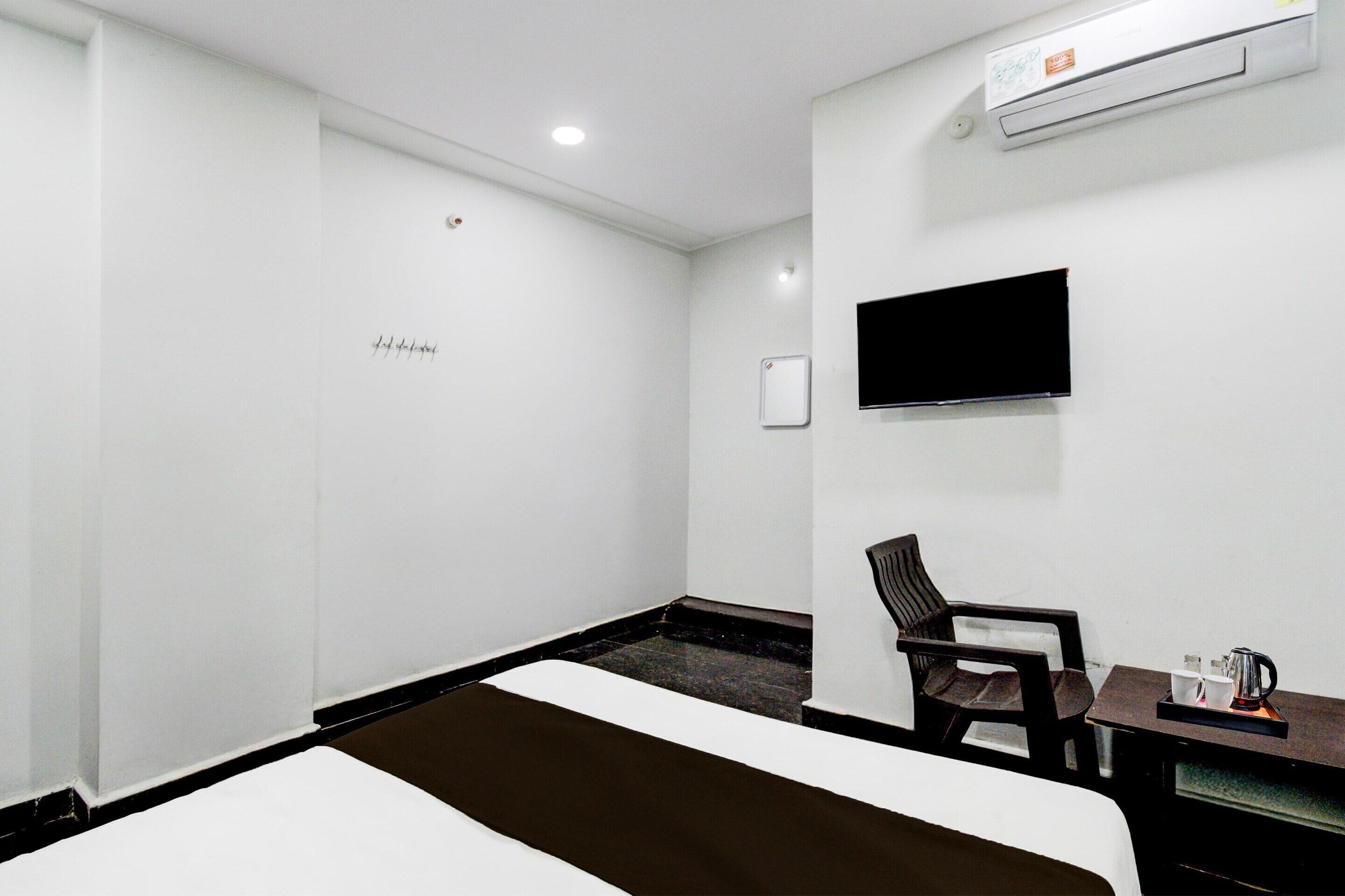 Ein Hotelzimmer mit Bett, Schreibtisch mit Stuhl, einem flachbildfernseher an der Wand und einer Klimaanlage.