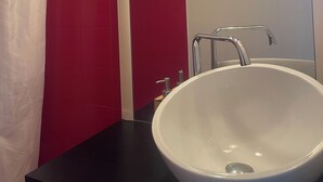 A bathroom with a white sink, red tiles, and a mirror. - Sea view apartment facing the beach (Clohars-Carnoët)