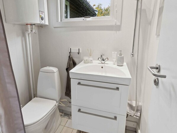 Une petite salle de bain comprenant des toilettes, un lavabo et une douche.