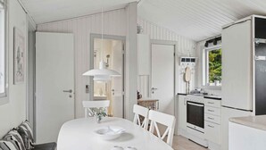 Eine moderne Küche mit weißen Schränken, einem Esstisch mit Stühlen, einem eingebauten Ofen und einem Kühlschrank.
