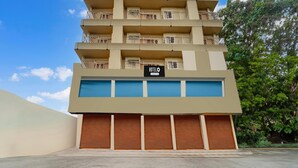 A multi-story hotel with balconies, a sign indicating it is a hotel, and a garage entrance. - Classic With Balcony Olive Residency (Kottayam)