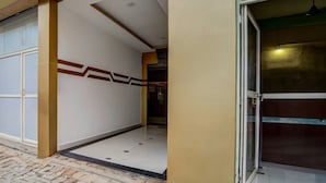 A building entrance with a tiled floor, a glass door, and a wall with a geometric pattern. - Classic With Balcony Olive Residency (Kottayam)