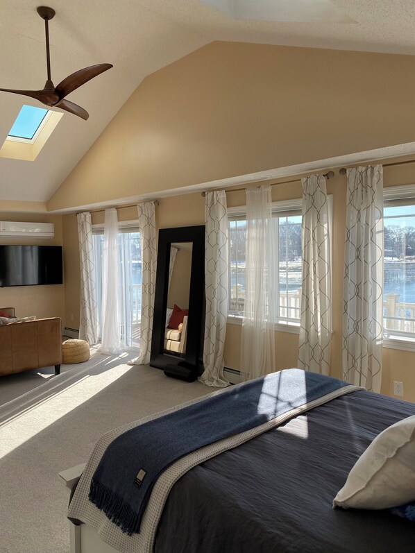 Une chambre à coucher avec un lit, un ventilateur de plafond, un grand miroir et une vue sur un paysage enneigé par les fenêtres.