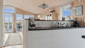 A modern kitchen with wooden paneling, a large island, and a view to the outside. - 4 Star Holiday Home in Slagelse (Slagelse)