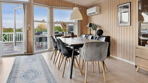 A modern dining area with a wooden ceiling, large windows, and a view of the outdoors. - 4 Star Holiday Home in Slagelse (Slagelse)