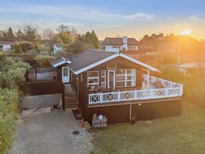 A two-story wooden house with a balcony, a garage, and a driveway.