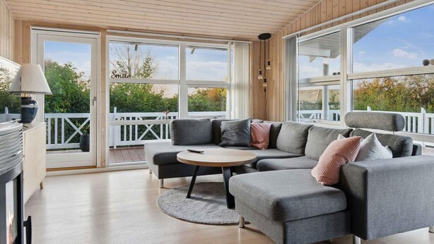 A modern living room with a sectional sofa, a round coffee table, and a fireplace. - 4 Star Holiday Home in Slagelse (Slagelse)
