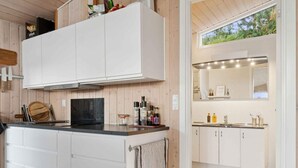 A modern kitchen with white cabinetry, a black countertop, and a window above the sink. - 4 Star Holiday Home in Slagelse (Slagelse)