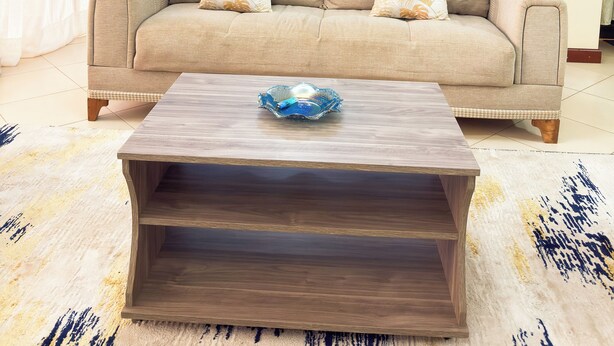 Ein Wohnzimmer mit einem beigen Sofa, einem Holztisch und einer blauen Wand.