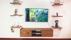 Ein Flachbildfernseher an der Wand befestigt, umgeben von Holzböden mit verschiedenen Dekorationselementen.