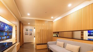 A modern living room with a flat-screen TV, wooden panel wall, and a sofa. - Stylish Spacious condo in charming Baguio for your getaway (Baguio)