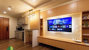 A modern kitchen with wooden cabinets, a built-in island, and a flat-screen TV mounted on the wall. - Stylish Spacious condo in charming Baguio for your getaway (Baguio)