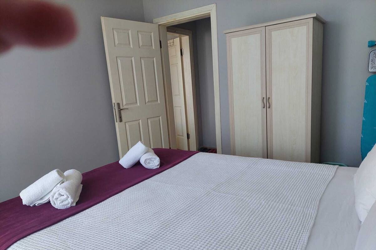 A hotel room with a bed, a wardrobe, and a door.
