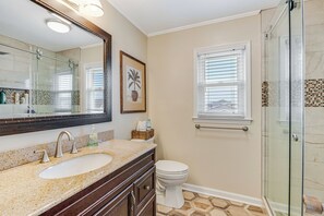 Une salle de bain avec une douche à parois de verre, un lavabo avec un plan de toilette en marbre et des toilettes.
