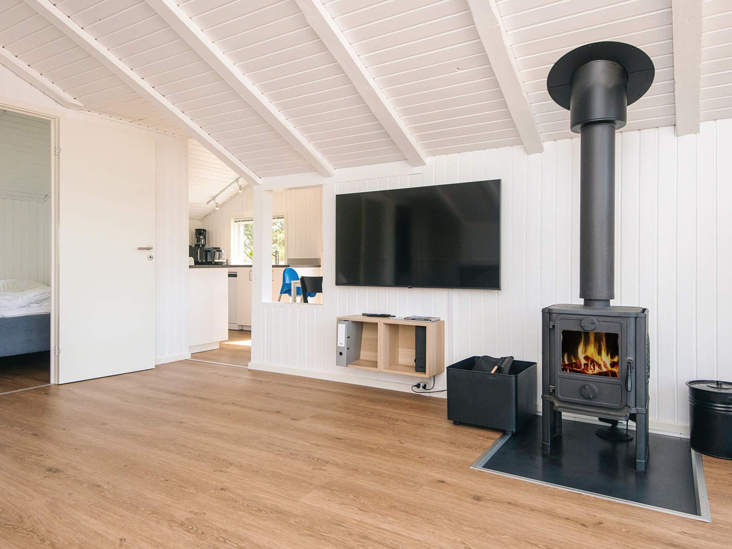Ein modernes Interieur mit Kaminofen, Flachbildfernseher und Küchenzeile.