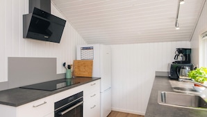 Een moderne keuken met witte kasten, een inbouwoven, een magnetron en een koffiezetapparaat.