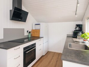 Eine moderne Küche mit weißen Schränken, einem Backofen, einer Mikrowelle und einer Kaffeemaschine.