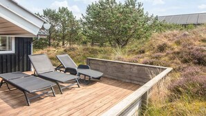 Een terras met lounge stoelen en een houten rand.