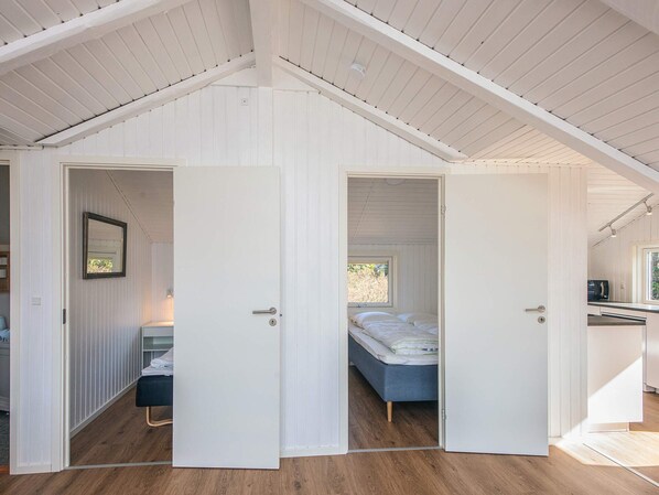 Een slaapkamer in loftstijl met een schuine kap, een bed, een bankje en een raam.