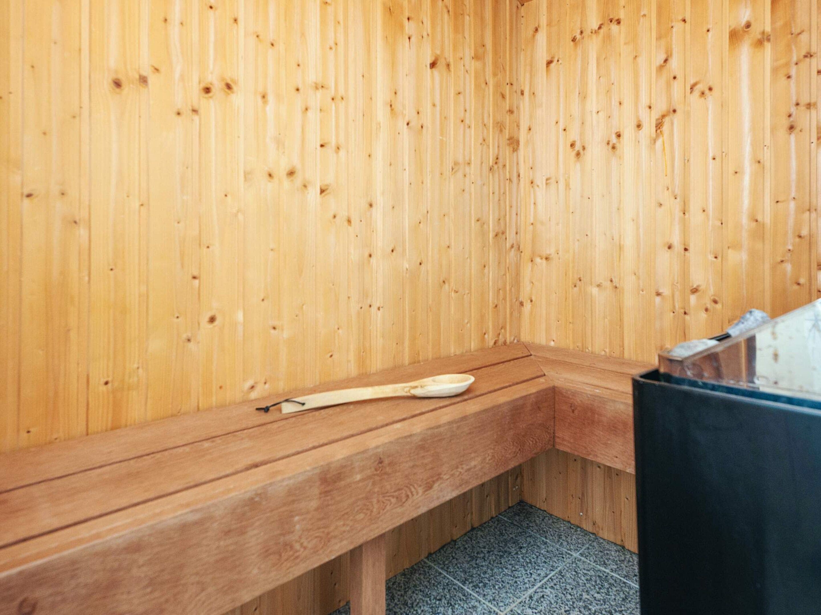 A wooden sauna with a bench and a wooden spoon.