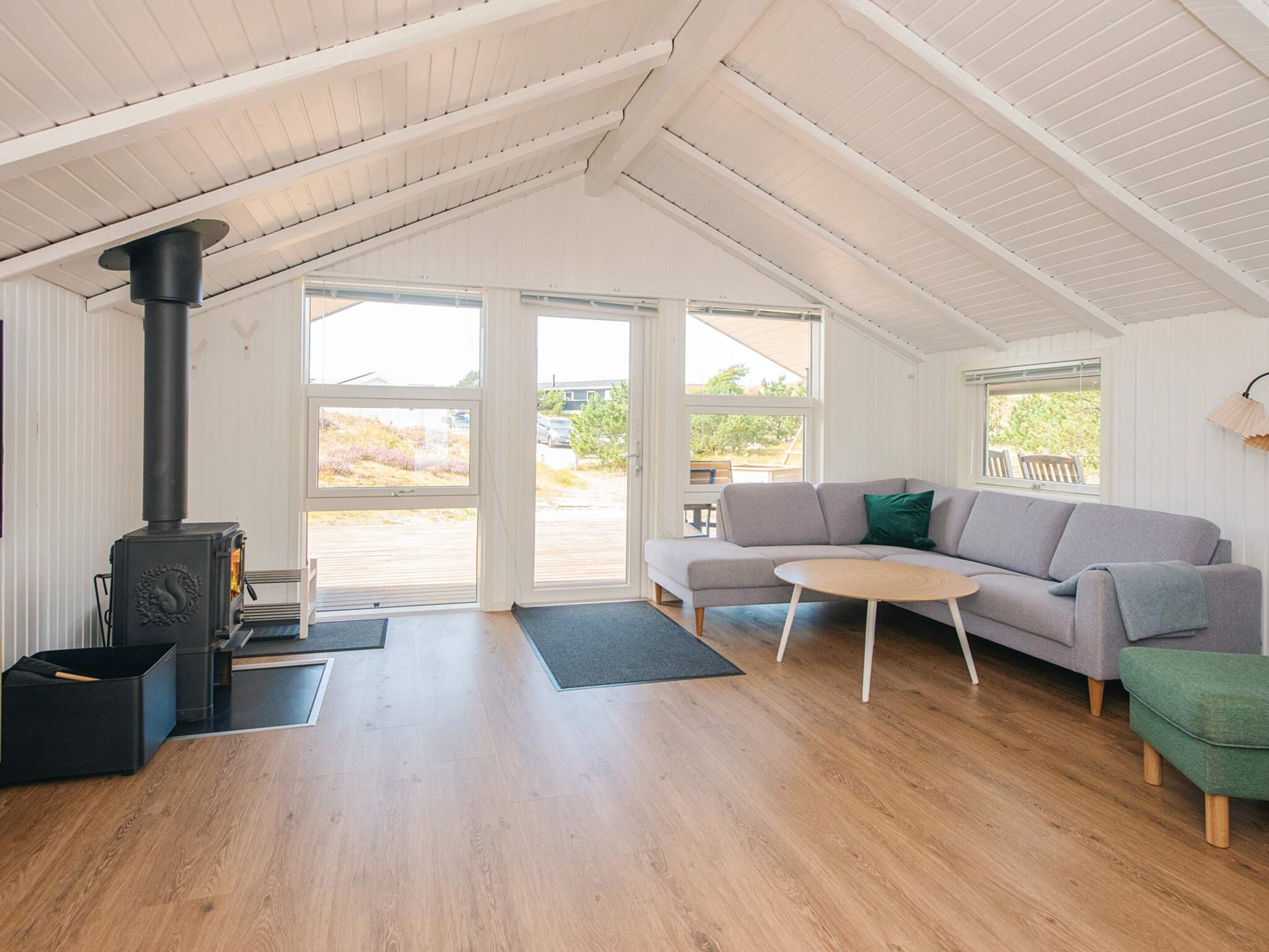 Un salon moderne avec un plancher en bois, un canapé, une petite table ronde et un poêle à bois noir.