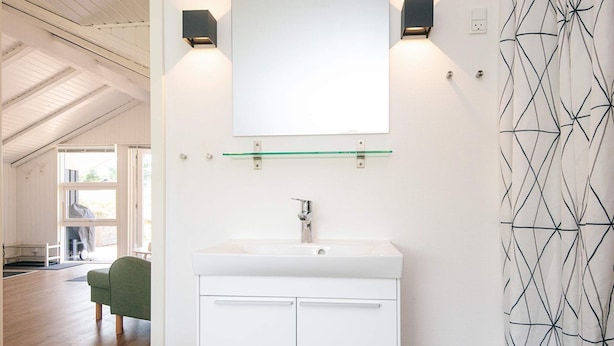 Een moderne badkamer met een witte wastafel, een spiegel erboven en twee wandlampen.