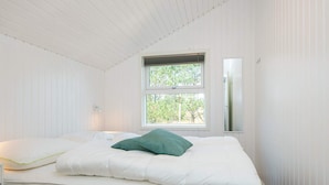 Een slaapkamer met een bed, een raam en een spiegel aan de muur.