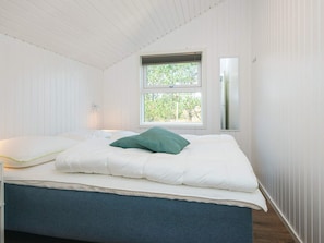 Ein Schlafzimmer mit einem Bett, einem Fenster und einem Spiegel an der Wand.