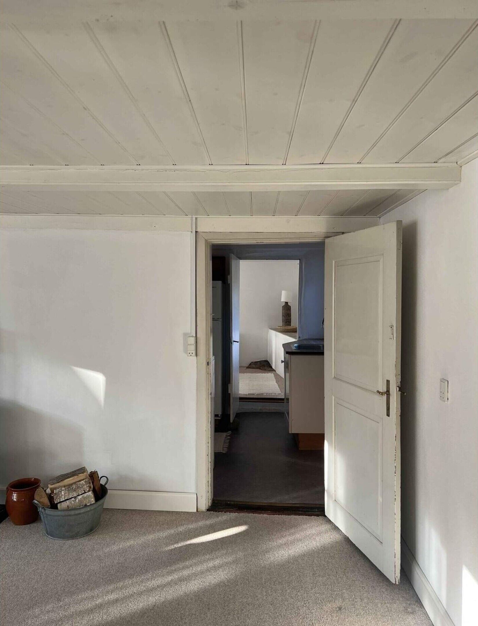 A hallway with a door leading to a kitchen area.