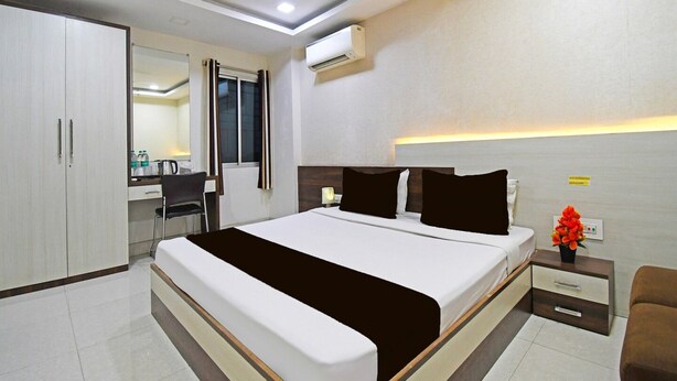 A modern hotel room with a bed, bedside table, nightstand, and a desk with a chair. - Deluxe With Twin Bed Hotel Amrit Plaza (Dhanbad)