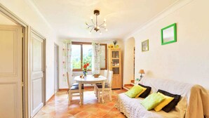 A room with a dining table, chairs, a sofa, a lamp, and a ceiling light fixture.