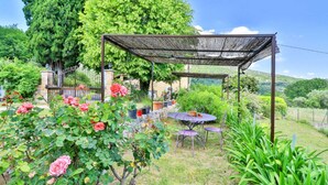 A garden with a pergola, a table, and chairs.