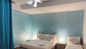 A bedroom with two beds, a nightstand, a ceiling fan, and a blue curtain. - Venice House (Venezia)