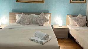 A double bed with a white comforter and two pillows, a nightstand with a lamp, and two framed paintings on the wall. - Venice House (Venezia)