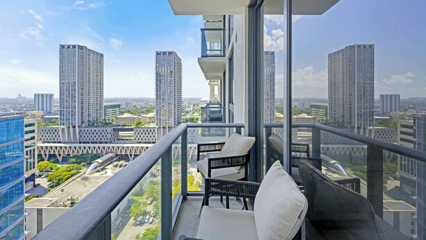 Een balkon met uitzicht op hoge gebouwen, een stoel en een tafel.