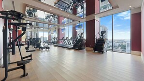 Een sportschool met trainingsapparatuur, grote ramen en uitzicht over de stad.