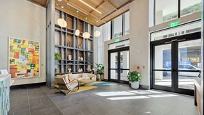 Een moderne lobby met een receptiebalie, een zithoek, een boekenkast en een groot raam.