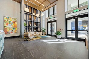 A modern lobby with a reception desk, a seating area, a bookshelf, and a large window. - Miami Worldcenter Chic - Rooftop Hot Tub (Miami)