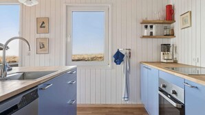Eine Küche mit Holzbalkendecke, einem Fenster mit Aussicht, einem Spülbecken, Schränken und einer Kaffeemaschine.