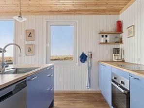 A kitchen with a wooden ceiling, a window with a view, a sink, cabinets, and a coffee maker. - 4 Star Holiday Home in Spottrup (Spøttrup)